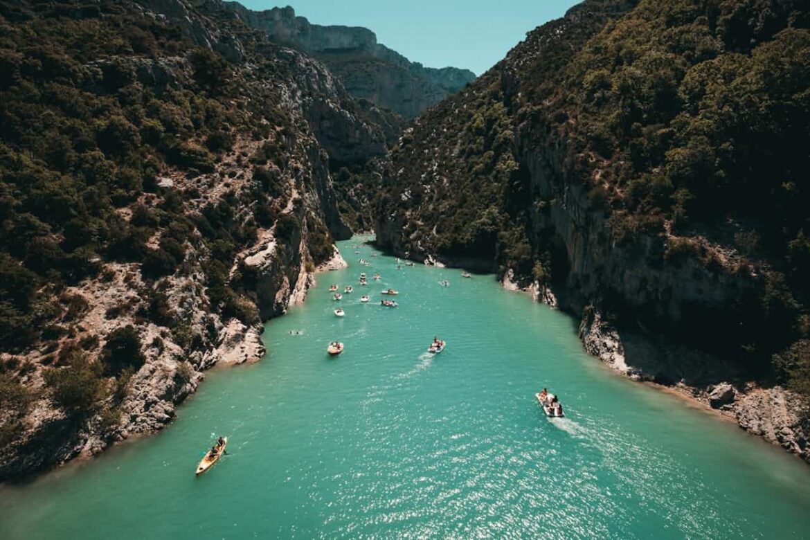 Un bateau de plaisance naviguant sur une rivière calme, bordée d'arbres verdoyants sous un ciel bleu, typique des destinations nautiques fluviales