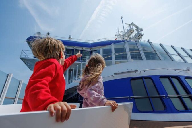 Deux enfants sur le pont d'un ferry admirent le navire, une scène typique de l'expérience de voyager avec des enfants en bateau.
