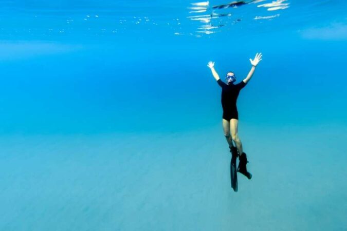 Un homme en combinaison de plongée évolue librement dans les eaux cristallines, entouré par les amateurs de plongée.