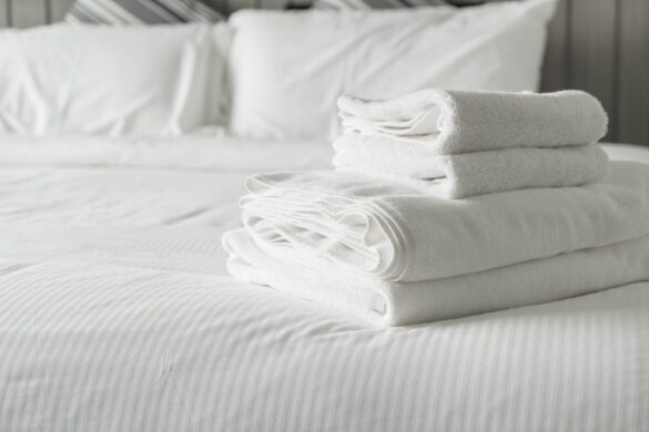 Pile de serviettes de bain blanches soignées posée sur une Couette Hôtellerie impeccable dans une chambre d'hôtel élégante.